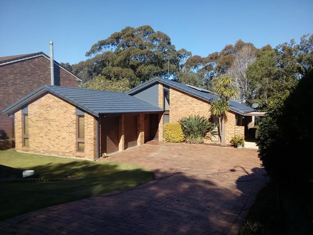 The same brick house with a clean dark charcoal tile roof, Twilight Shadow, after restoration.