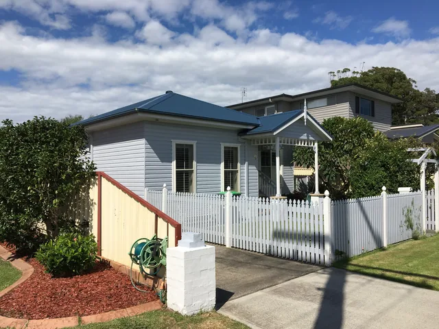 The same cottage with a deep navy metal roof, Deep Ocean Blue, after restoration.
