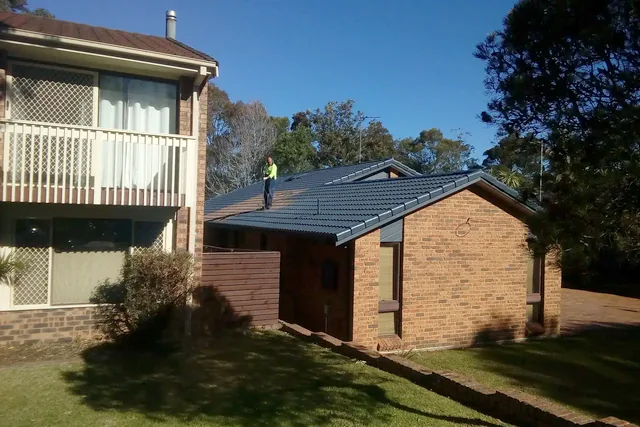 Roofer standing on a charcoal tile roof during a job.